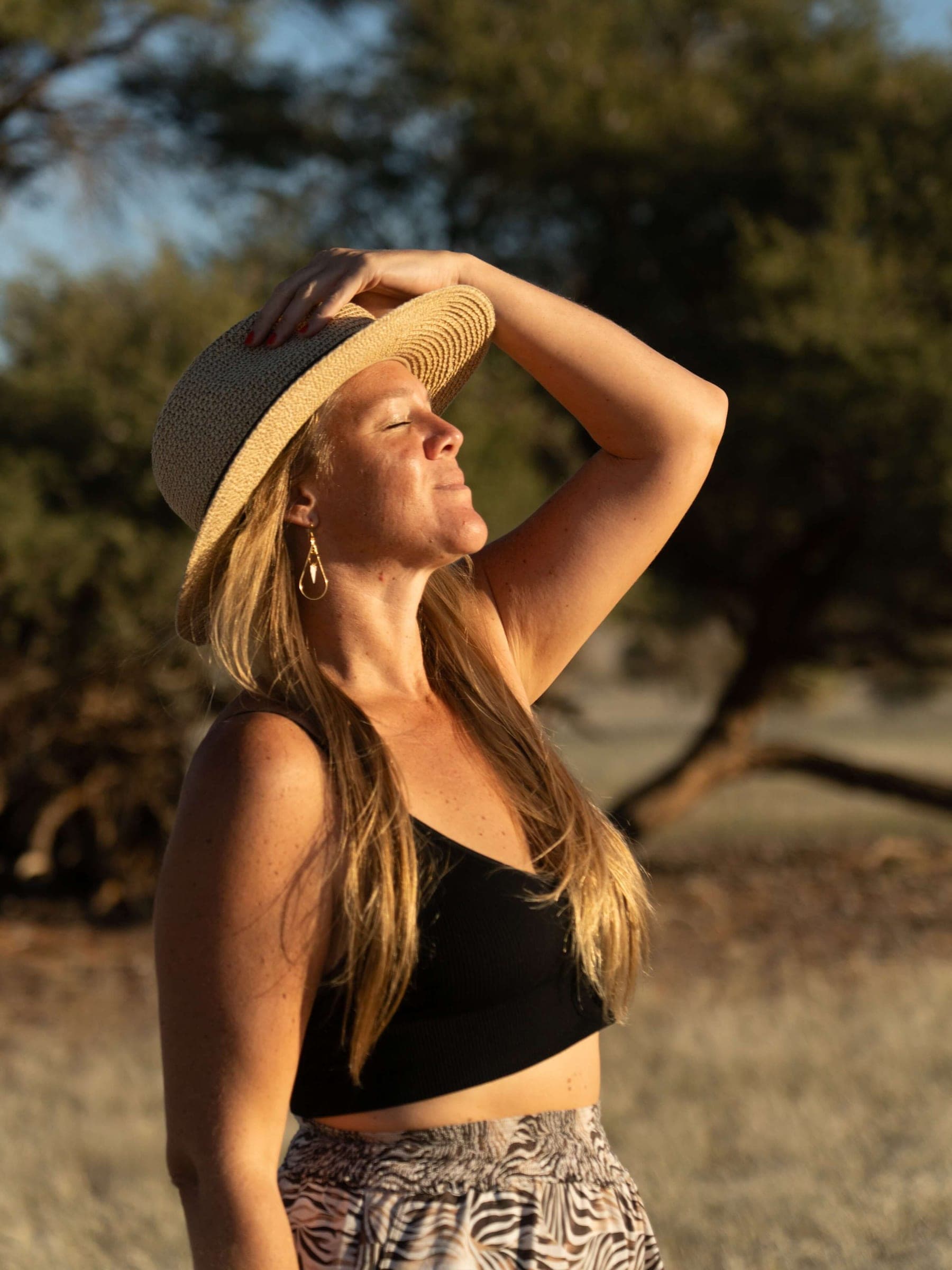 Portrait de Léa, chapeau de paille, la main en visière
