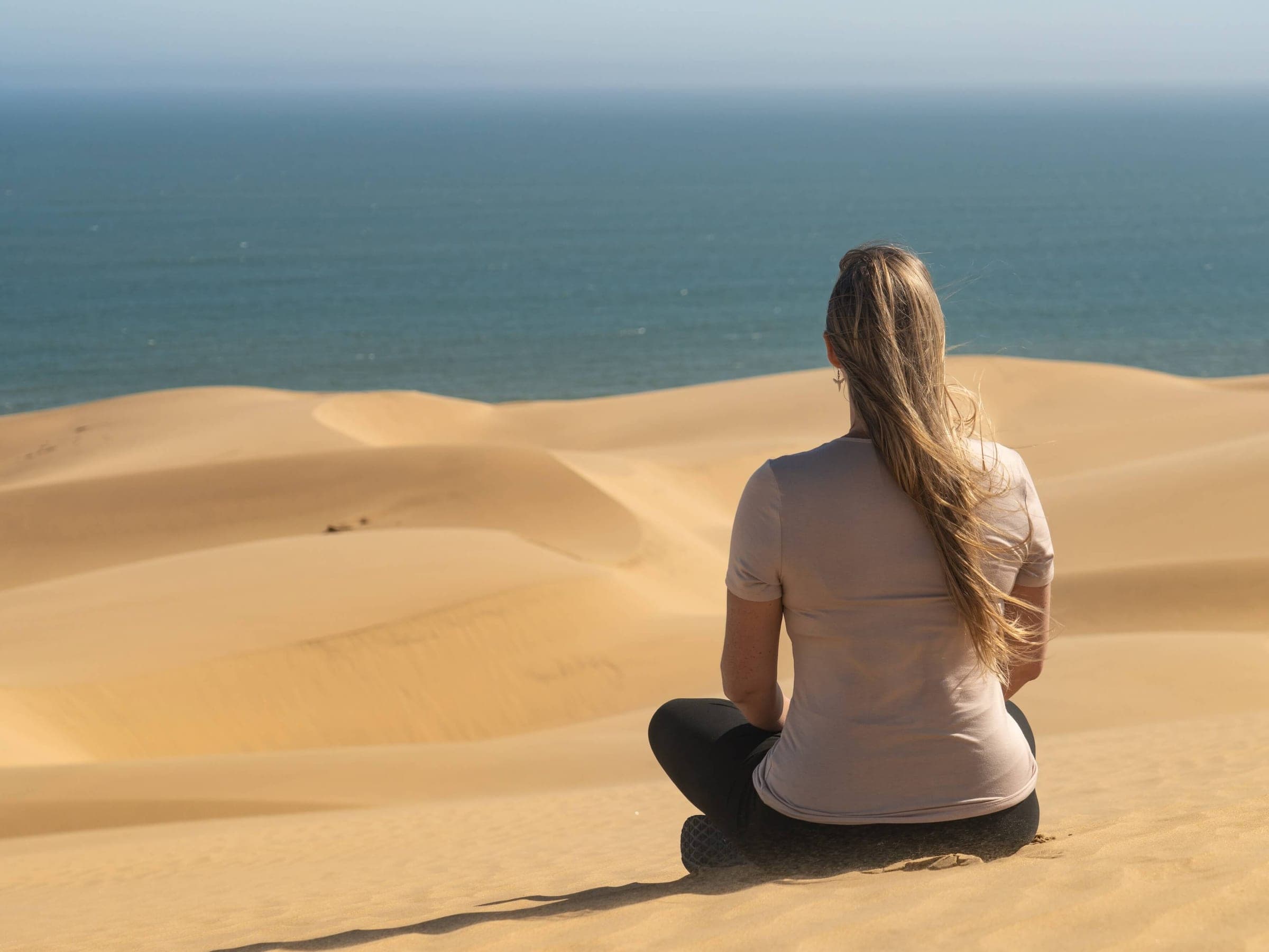 Léa assise au sommet d'une dune, face à l'océan